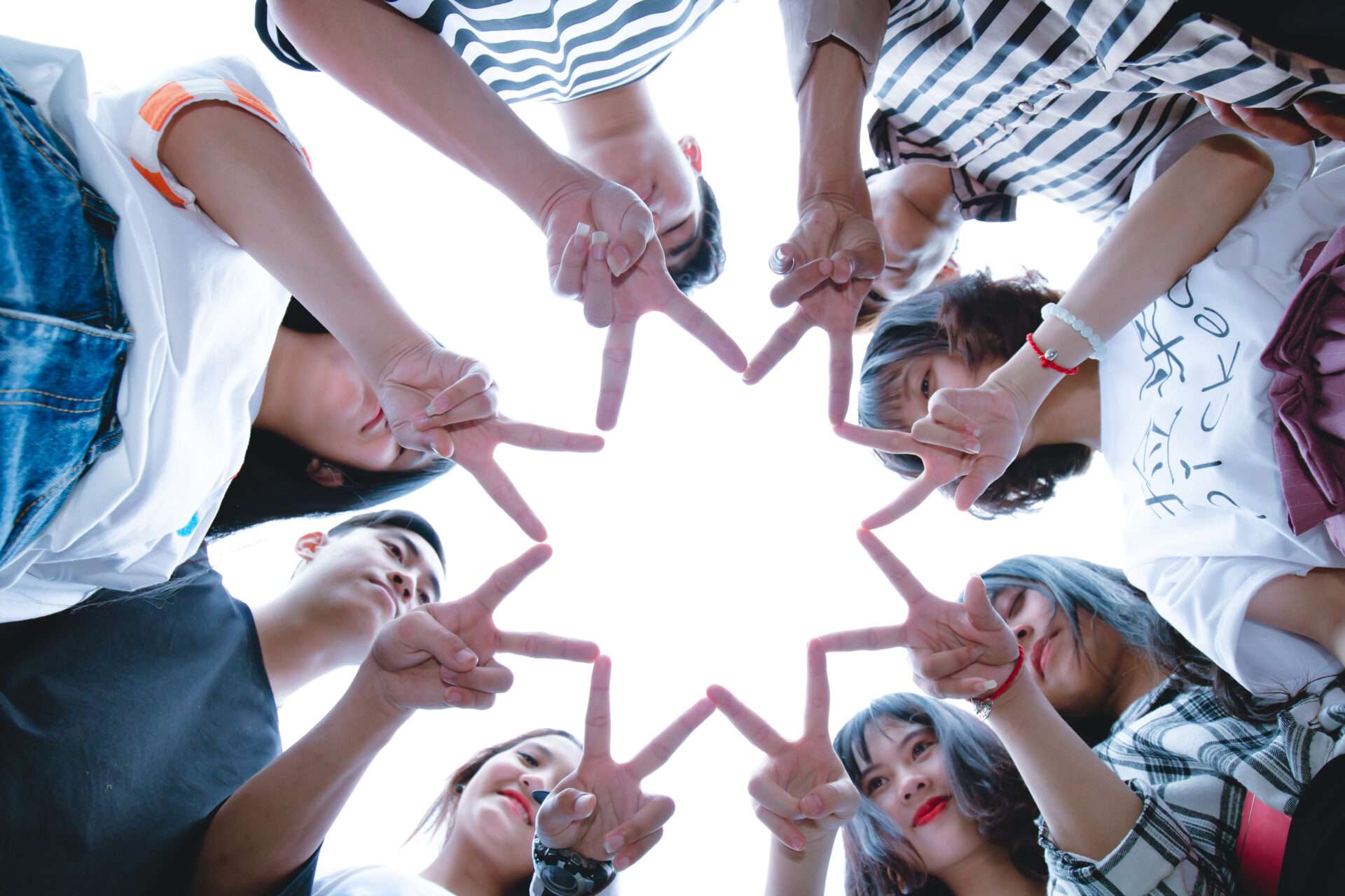 Group of young people standing in a circle many a collective star with their fingers